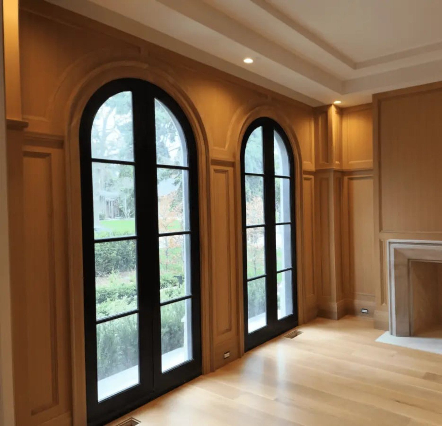 Arched black doors framed by detailed wood trim and wall panelling