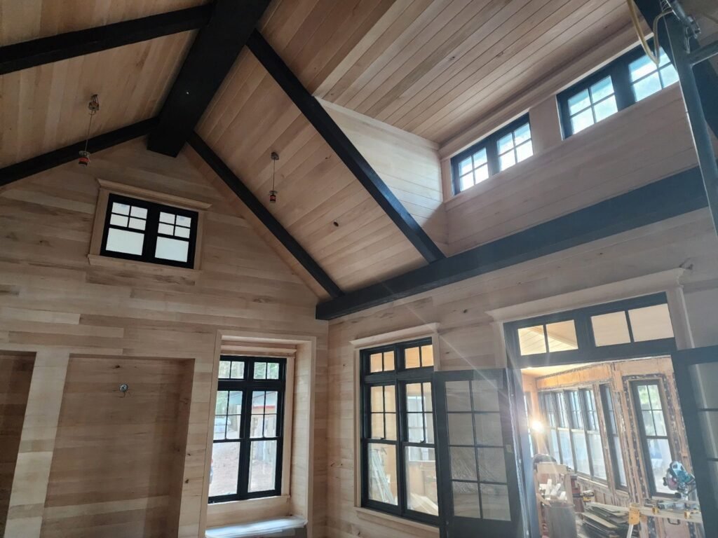 Tongue and groove walls and ceiling with dark beams in a custom home under construction