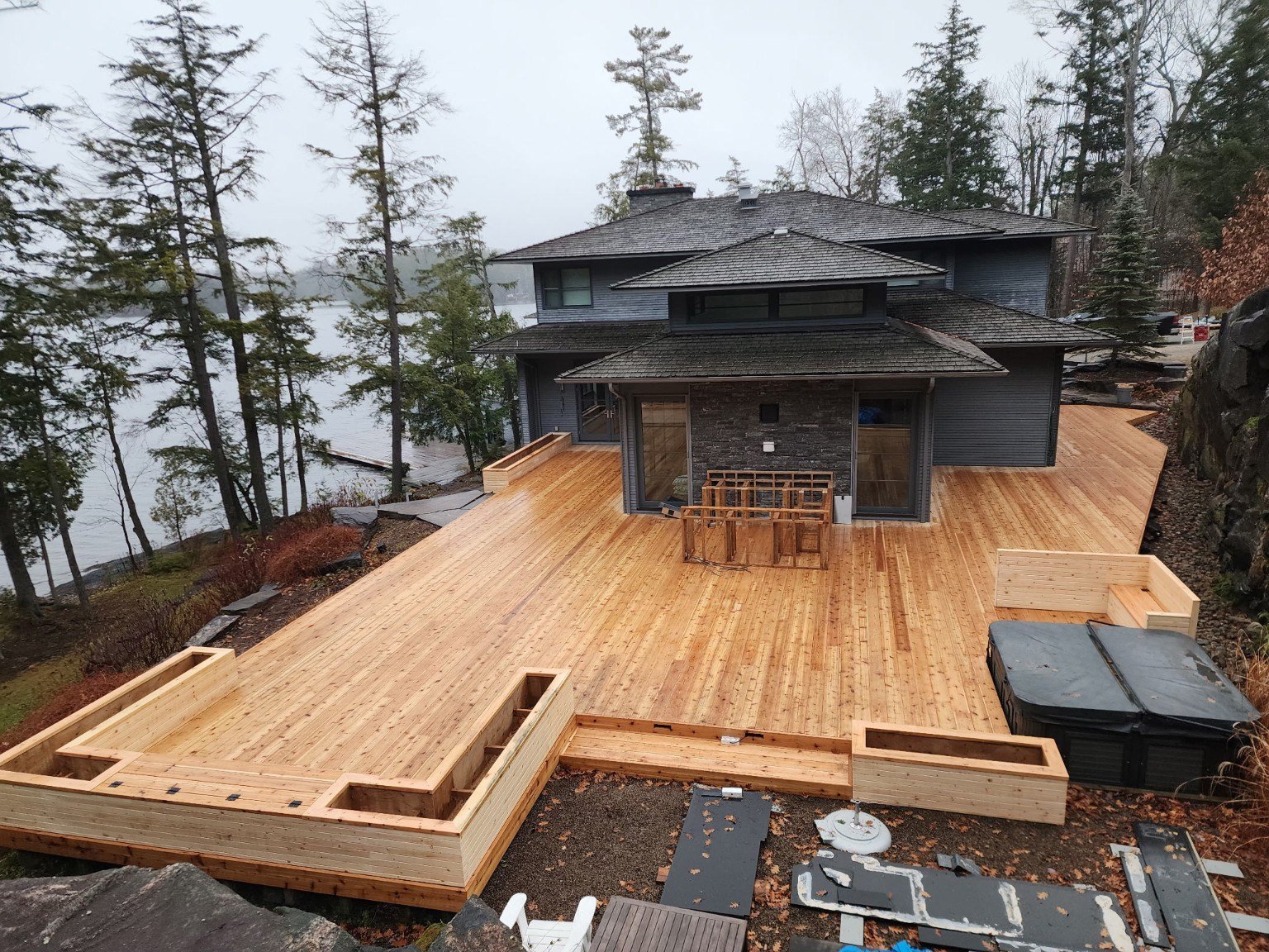 Large wood deck wrapping a waterfront cottage, pictured during construction
