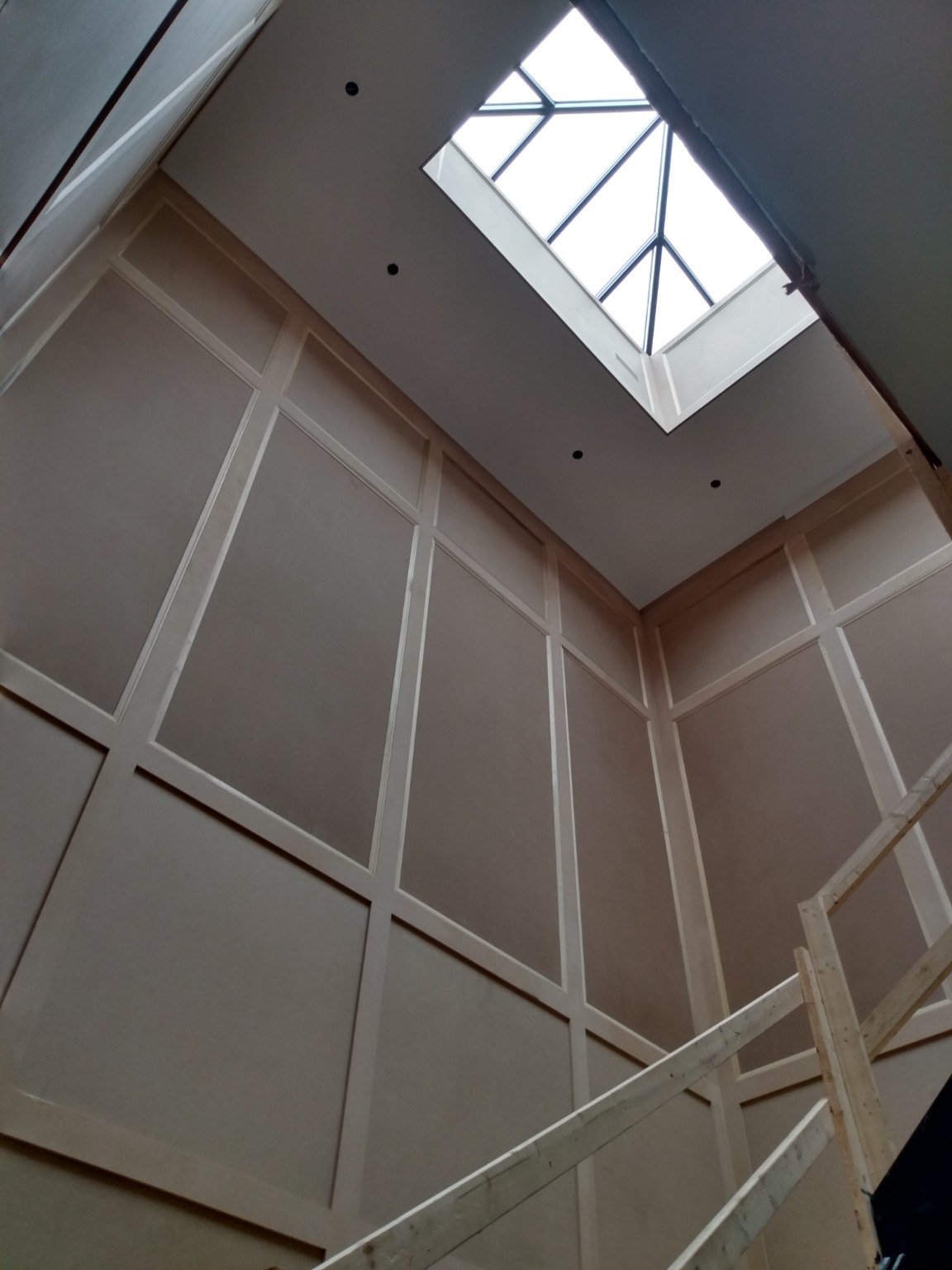 Tall stairwell wall panelling rising toward a skylight